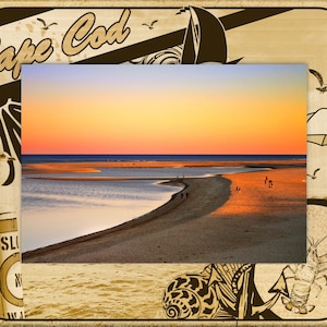 May include: A vintage-style picture frame with a seashell, anchor, and lobster design. The frame features a photo of a beach scene with a sunset over the ocean and a sandy beach.