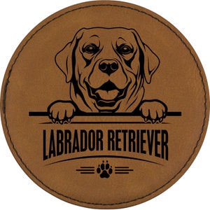 May include: Brown leather coaster with a black silhouette of a Labrador Retriever peeking over the top. The text "Labrador Retriever" is printed below the dog, with a paw print and three lines underneath.