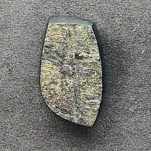 May include: A dark gray and gold gemstone cabochon with a rough, irregular shape.