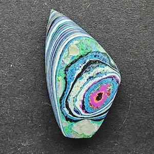 May include: A colorful, abstract, agate cabochon with a swirling pattern of blue, green, pink, and white. The cabochon is shaped like a teardrop and has a smooth, polished surface.