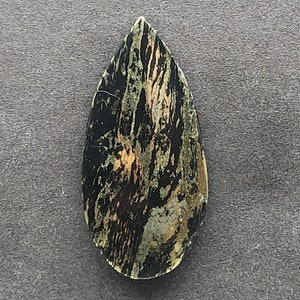 May include: A teardrop-shaped cabochon of green, black, and gold serpentine with a swirling pattern.