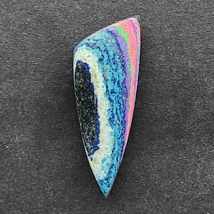 May include: A colorful, iridescent, teardrop-shaped cabochon with a black, white, blue, pink, and green pattern.
