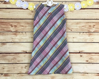 May include: A sleeveless dress with a diagonal plaid pattern in shades of pink, blue, yellow, and gray. The dress has a small embroidered butterfly on the front with the text "HIGH STREET" underneath.