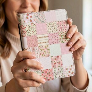 May include: A rectangular protective case featuring a patchwork design of various pink and white patterns, including small strawberries, cherries, gingham checks, and polka dots, with a smooth finish and a black spine edge on the left side.