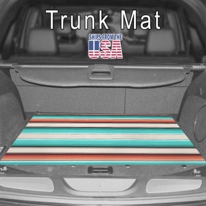 May include: A rectangular trunk mat featuring a horizontal striped pattern in shades of teal, cream, and coral orange. The mat is positioned inside the cargo area of a vehicle. The text "Trunk Mat" and "SHIPS FROM THE USA" are visible.