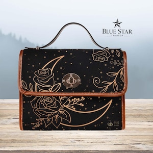 May include: A black handbag with a brown leather trim and a top handle. The bag features a gold-toned twist-lock closure and a printed design of roses, crescent moons, and stars in a metallic gold color. The text Blue Star Trader is visible.