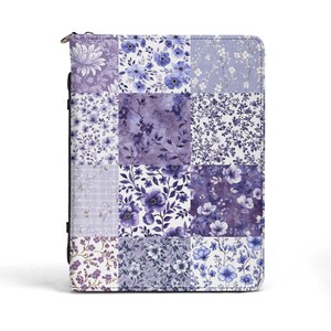 May include: A zippered case with a patchwork design featuring various floral patterns in shades of purple and blue. The case has a black spine and a silver zipper. The floral patterns include stylized flowers and leaves.