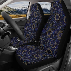 May include: A pair of car seat covers featuring a dark blue and black celestial pattern. The design includes gold-colored suns with faces, crescent moons with faces, and various star shapes scattered across a deep space-inspired background.
