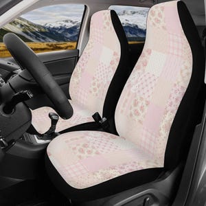 May include: Car seat covers with a patchwork design in shades of pink, cream, and white. The covers feature floral and geometric patterns, with black trim. The steering wheel and dashboard are visible in the car interior.