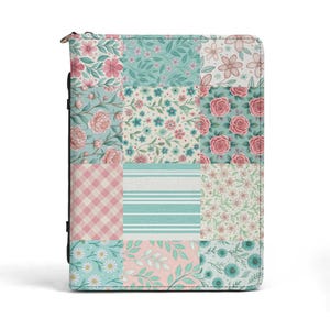 May include: A floral patchwork journal cover with a zipper closure. The cover features a variety of patterns, including pink roses, gingham, stripes, and floral designs in shades of pink, teal, and white. The journal is rectangular and appears to be made of fabric.