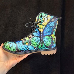 May include: Black lace-up boots with a colorful butterfly design. The butterfly has blue, green, and yellow wings.