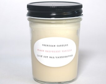 May include: A glass jar candle with a black lid and a white label that reads "CrenShaw Candles Black Raspberry Vanilla 100% Soy Wax/Handcrafted".