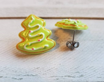 May include: A pair of green and white Christmas tree-shaped earrings with red and yellow sprinkles. The earrings are made of polymer clay and have silver posts.
