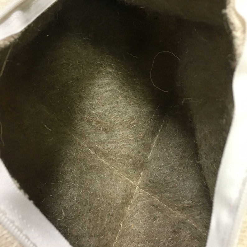 May include: The inside of a white canvas bag with a beige felt lining. The lining has a few loose threads.