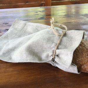 Puede incluir: Una hogaza de pan envuelta en una bolsa de tela de lino natural atada con una cuerda.