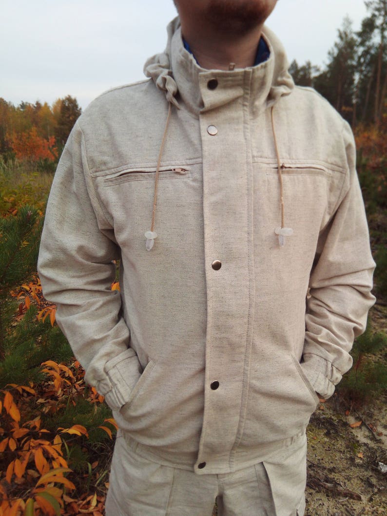 May include: A beige hooded jacket with a zip fastening and multiple pockets. The jacket has a drawstring hood and a button-up front.