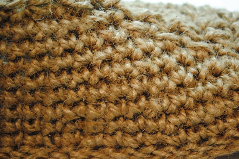 May include: Close-up of a woven jute fabric, showcasing a textured surface. The natural fibers are tightly interlaced, creating a dense, durable material. The color is a warm, earthy brown, suggesting a rustic or natural aesthetic.