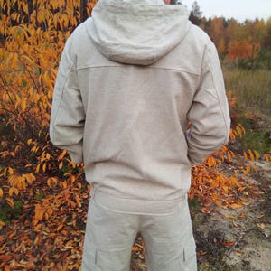 May include: A beige hooded jacket and matching shorts made of linen. The jacket has a zip closure and a drawstring hood. The shorts have two pockets on the sides.