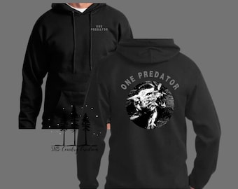 May include: Black hooded sweatshirt with a front pocket and drawstring. The back displays a circular graphic of a snarling wolf with the text "ONE PREDATOR". The front of the hoodie has the text "ONE PREDATOR" printed on the upper left chest.