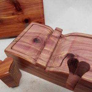 May include: A wooden box with a heart-shaped opening and a separate heart-shaped piece. The box is made of cedar wood and has a natural reddish-brown color.
