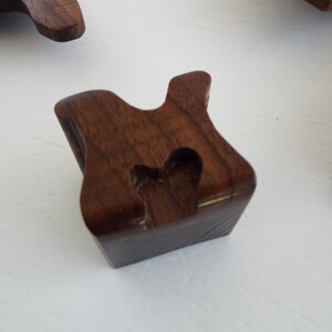 May include: A dark brown wooden block with a heart-shaped cutout. The block is shaped like a letter "H".