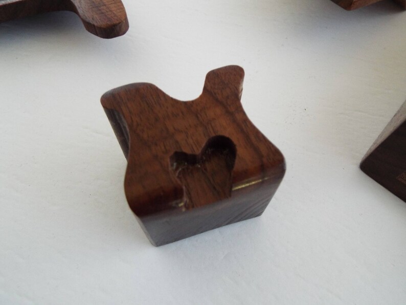 May include: A dark brown wooden block with a heart-shaped cutout. The block is shaped like a letter "H".