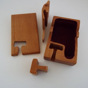May include: A wooden puzzle box with a red velvet interior. The box is made of five pieces that fit together to create a secure container.