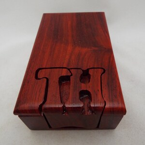 May include: A wooden box with a red finish and the letters "TH" carved into the top.