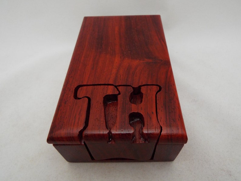 May include: A wooden box with a red finish and the letters "TH" carved into the top.