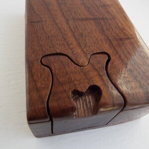 May include: A wooden puzzle box with a unique, intricate design. The box is made of dark brown wood and has a smooth, polished finish.