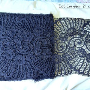 Può includere: Due rotoli di tessuto in pizzo blu navy con intricati motivi floreali e a volute. Il tessuto è largo circa 21 cm, come indicato dal testo "Ext Largeur 21 cm". Il pizzo è presentato su uno sfondo bianco.