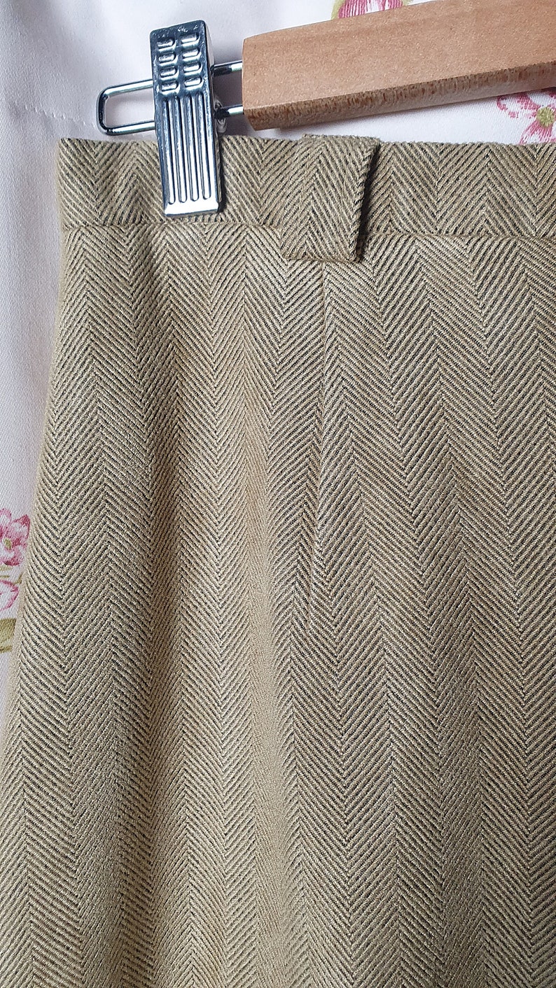 May include: A pair of brown herringbone patterned pants with a single button closure at the waist.