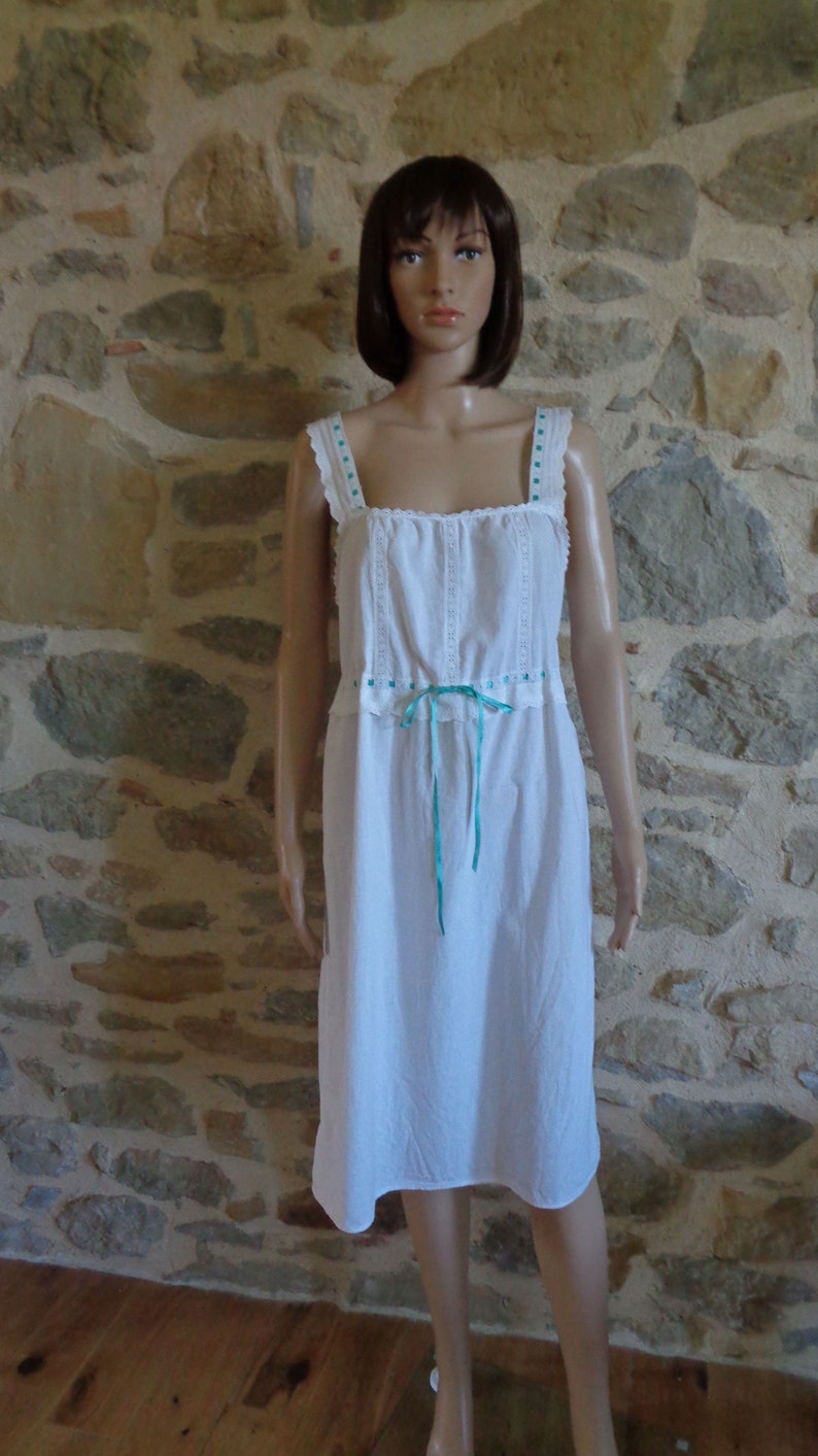 White cotton nightdress or full slip trimmed with broderie anglaise threaded with turquoise ribbon