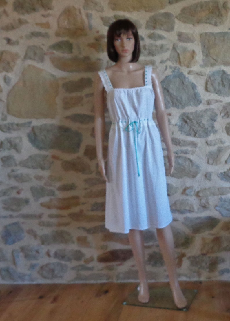 White cotton nightdress or full slip trimmed with broderie anglaise threaded with turquoise ribbon
