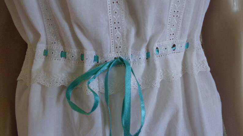 White cotton nightdress or full slip trimmed with broderie anglaise threaded with turquoise ribbon