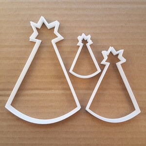 Peut inclure: Trois emportes-pièces en plastique blanc en forme de chapeaux de fête. Le plus grand emporte-pièce a un sommet pointu et un bord large. L'emporte-pièce moyen a un sommet pointu et un bord plus petit. Le plus petit emporte-pièce a un sommet pointu et un très petit bord.