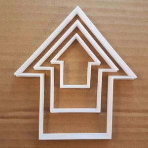 May include: White plastic cookie cutter shaped like a house with three different sized openings.