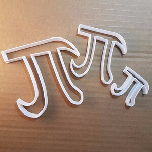 Könnte beinhalten: Ein Satz mit vier weißen Plastik-Ausstechern in Form des mathematischen Symbols Pi.