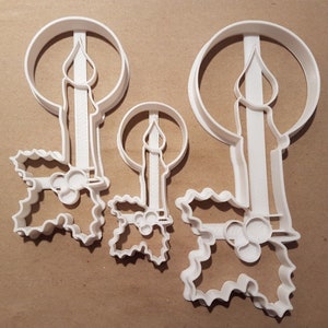 Può includere: Tre stampini per biscotti in plastica bianca a forma di candele con foglie di agrifoglio. Lo stampino più grande è alto 18 cm e il più piccolo 8 cm.