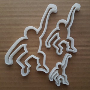 May include: A set of four white plastic cookie cutters shaped like monkeys in different poses. The cutters are designed to create cookies in the shape of monkeys.