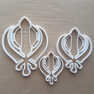 Peut inclure: Trois emporte-pièces en plastique blanc en forme du symbole sikh, Khanda. Les emporte-pièces sont de tailles différentes.