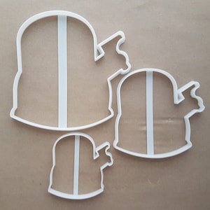May include: Three white plastic cookie cutters shaped like a ghost with a single eye. The cutters are different sizes, with the largest cutter at the top of the image and the smallest cutter at the bottom.