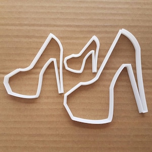 May include: Two white plastic cookie cutters shaped like high-heeled shoes.