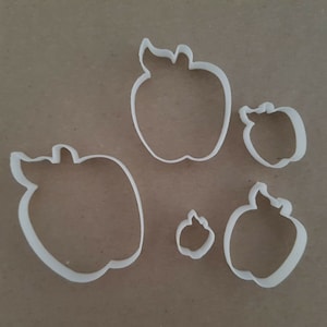 May include: Set of five white plastic apple-shaped cookie cutters of varying sizes.