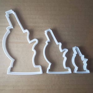 May include: Three white plastic cookie cutters shaped like microscopes of different sizes.