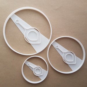 May include: Three white plastic cookie cutters in different sizes, each featuring a stylized design of a teardrop shape with a small circle at the top.