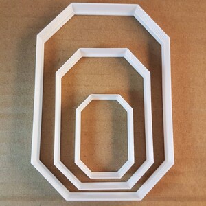 May include: Three white octagon-shaped cookie cutters of different sizes. The largest cutter is in the back, the medium cutter is in the middle, and the smallest cutter is in the front.