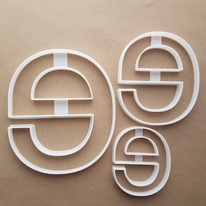 以下が含まれることがあります： 異なるサイズの「E」の文字の形をした、白いプラスチック製のクッキーカッターが3つあります。
