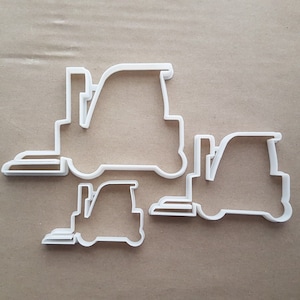 May include: Three white plastic cookie cutters shaped like forklifts of different sizes. The largest cutter is about 12.5 cm long, the medium cutter is about 7.5 cm long, and the smallest cutter is about 5 cm long.