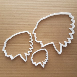 May include: Three white plastic cookie cutters shaped like Native American headdresses. The cutters are different sizes, with the largest cutter at the top of the image and the smallest cutter at the bottom.